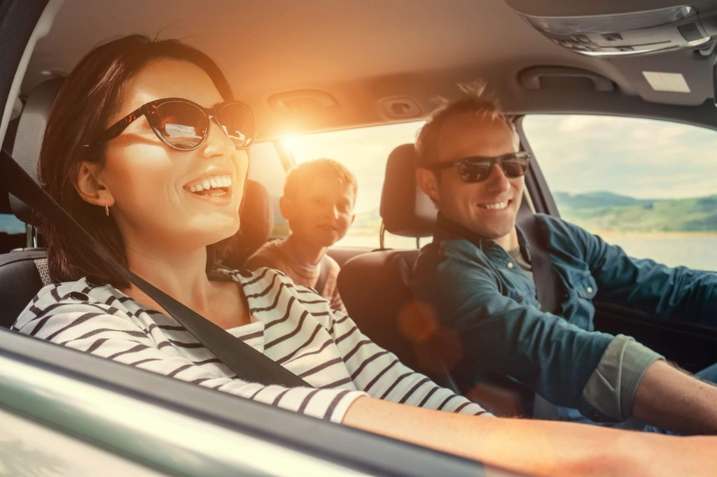 Happy family on a sunny road trip in a rental car